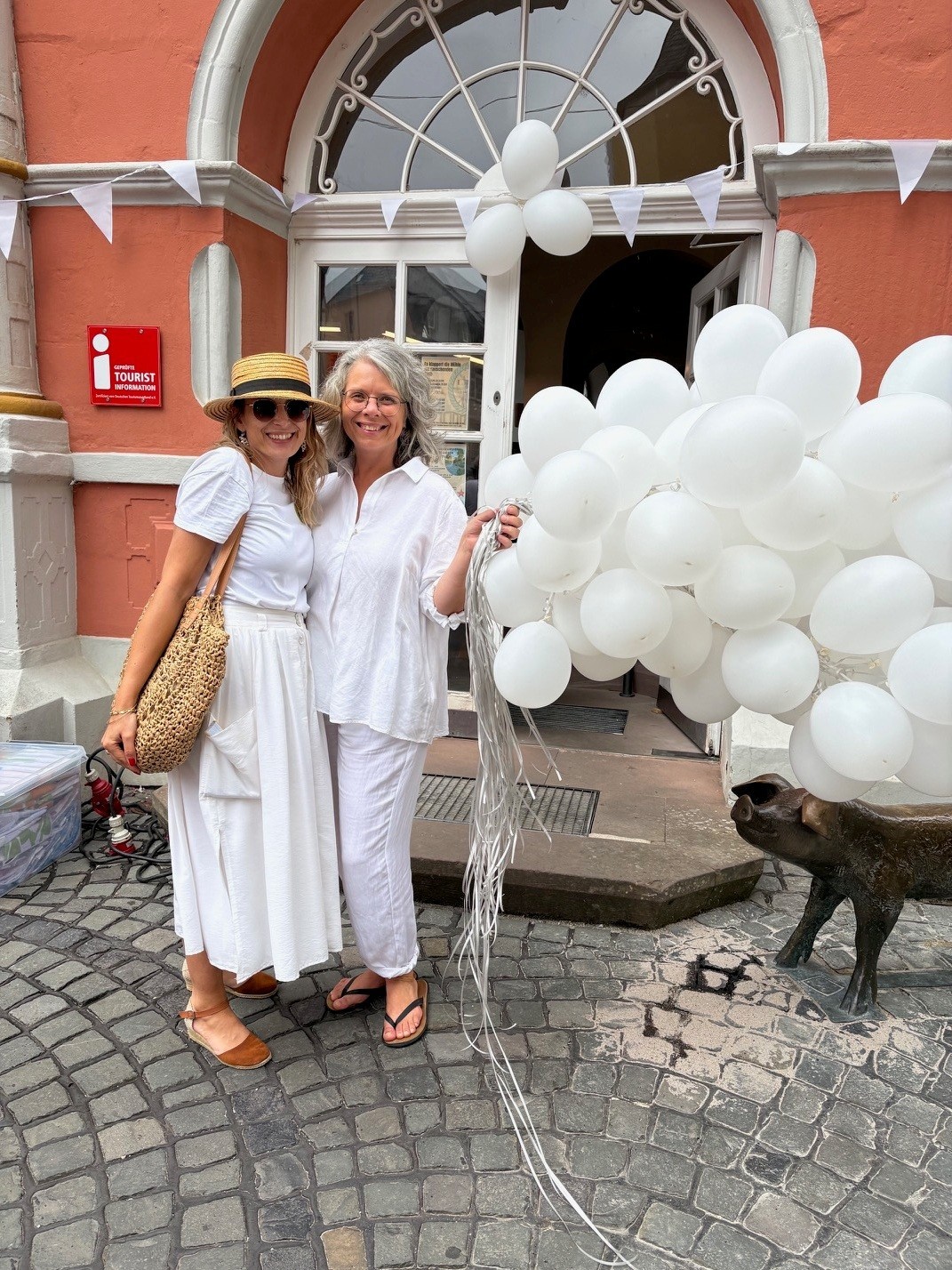 Dämmershoppen Das Bild zeigt zwei Personen vor dem Rathaus während der Veranstaltung Dämmershoppen mit weißen Luftballons.