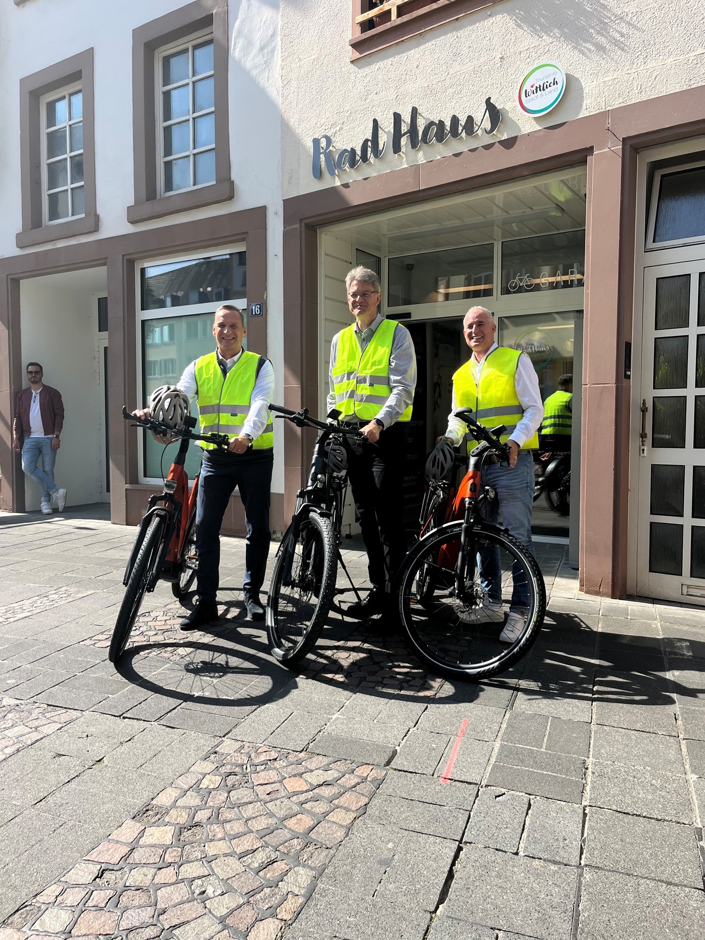 Das Foto zeigt Bürgermeister Rodenkirch mit Bundesverkehrsminister Schnieder und Landtagsabgeordneten Junk vor dem "Rad Haus" in der Burgstraße.
