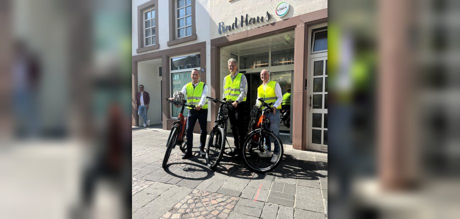 Das Foto zeigt Bürgermeister Rodenkirch mit Bundesverkehrsminister Schnieder und Landtagsabgeordneten Junk vor dem "Rad Haus" in der Burgstraße.