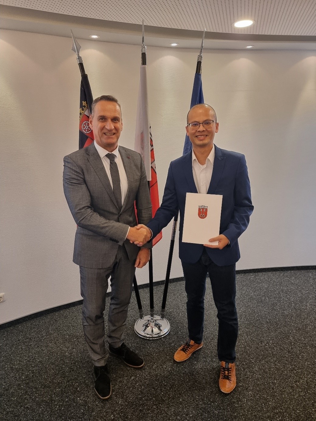 Bürgermeister Joachim Rodenkirch ernennt Hoang Huy Nestor (links) zum Beamten auf Lebenszeit.