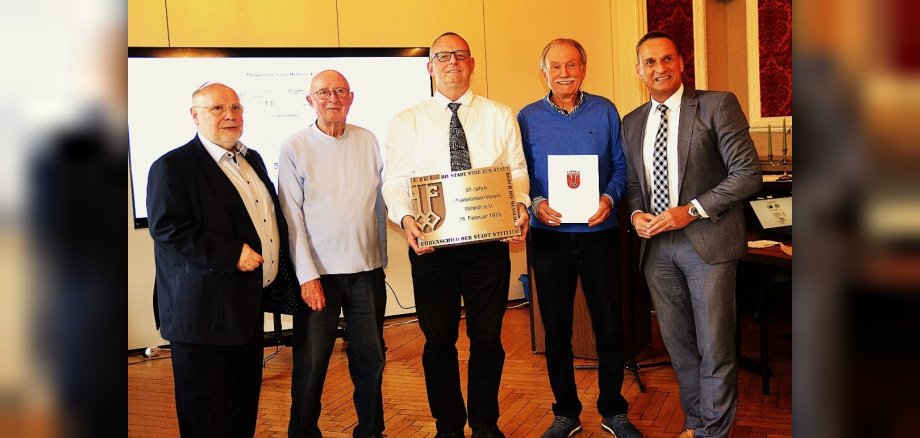 Das Foto zeigt Bürgermeister Rodenkirch mit Vertretern des Philatelistenvereins bei der Übergabe des Ehrenschild der Stadt Wittlich.