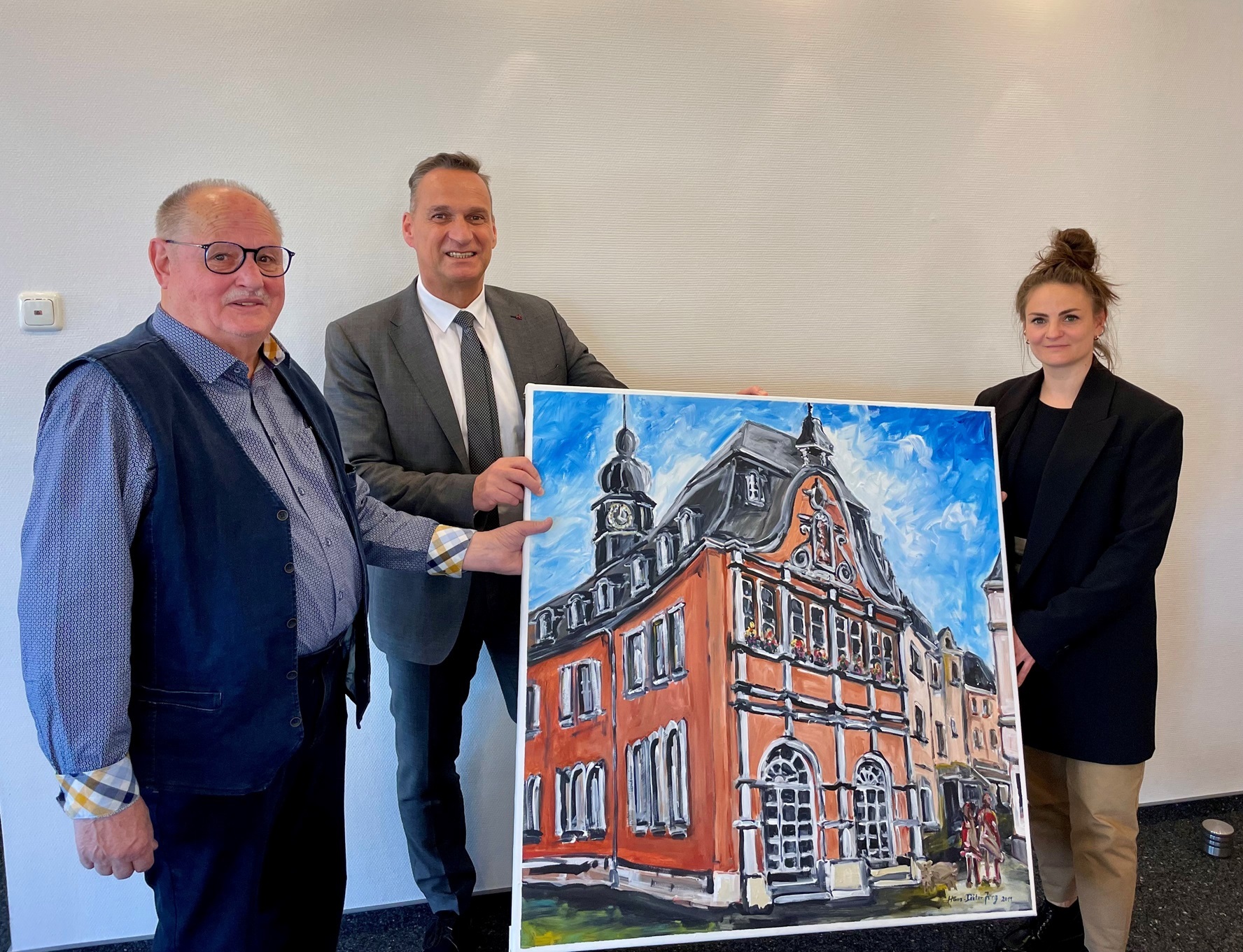 Das Foto zeigt den Künstler Hans-Dieter Jung bei der Übergabe eines Gemäldes des Alten Rathauses mit Bürgermeister Joachim Rodenkirch und Leiterin des Kulturamtes Nina Dusartz de Vigneulle.