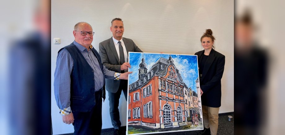 Das Foto zeigt den Künstler Hans-Dieter Jung bei der Übergabe eines Gemäldes des Alten Rathauses mit Bürgermeister Joachim Rodenkirch und Leiterin des Kulturamtes Nina Dusartz de Vigneulle.