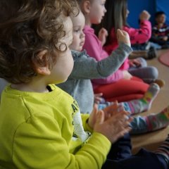 Die Kinder sitzen im zusammen im Kreis und klatschen in die Hände