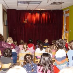 Die Kinder und Erzieher sitzen vor der Bühne und schauen Schnecke Meme auf der Bühne zu die mit ihnen spricht