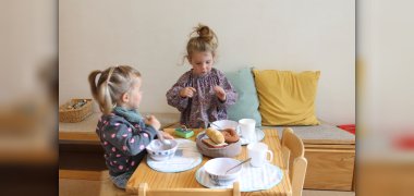 Auf dem Bild spielen zwei Kinder am Tisch mit Küchenspielsachen.