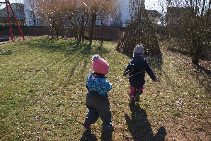 Zwei Mädchen laufen als "Pferde" hintereinander mit einer "Pferdeleine zwischen beiden