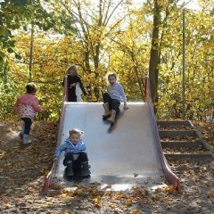 Auf dem Bild sieht man vier Kinder die die Rutsche herunter rutschen und den Hügel daneben nach oben gehen.