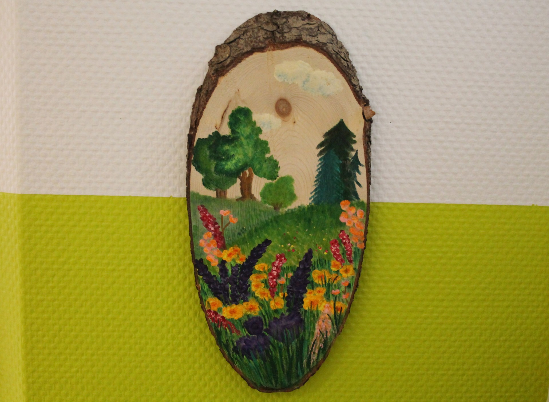 Wiesengruppe Auf dem Bild sieht man das Symbol der Wiesengruppe. Es stellt eine Wiese mit Blumen dar. Im Hintergrund sind Bäume zu sehen.