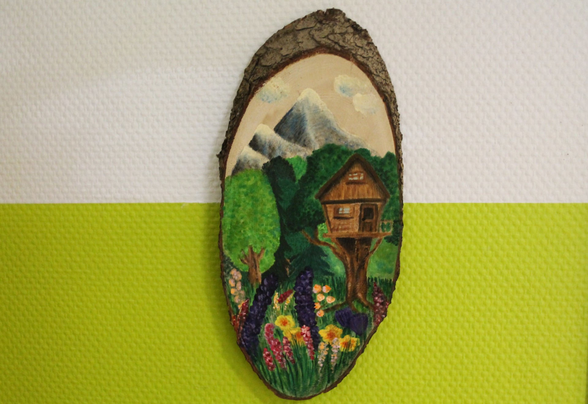 Baumhausgruppe Auf dem Bild sieht man das Symbol der Baumhausgruppe. Es ist ein Baumhaus im Vordergrund zu sehen und drum herum eine Wiese und Bäume. Im Hintergrund sind Berge gezeichnet.