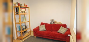 Leseraum Auf dem Bild sieht man den Leseraum. An der Wand Steht ein Regal mit Büchern und eine Couch zum sitzen.