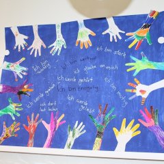Ein blaues Plakat mit Händen der Kinder die bunt angemalt wurden von den Kindern. In der Mitte sind verschiedene Kinderrechte aufgeschrieben,