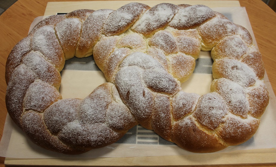 Das Bild zeigt eine riesige geflochtene Martinsbrezel mit Zucker auf einem Tisch.