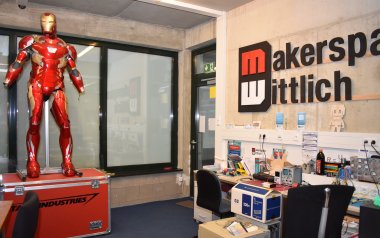 Das Bild zeigt eine Werkstatt, in der ein Bereich für Elektro-Arbeiten sowie ein Iron-Man-Anzug zu sehen sind. 