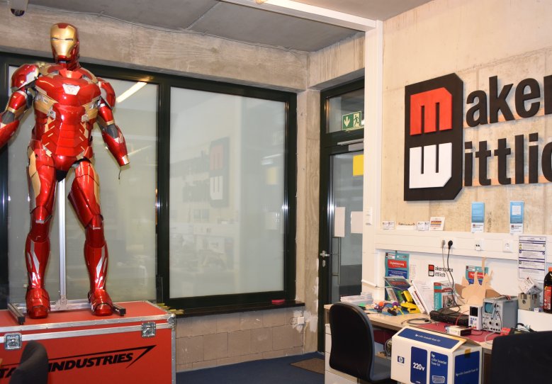 Das Bild zeigt eine Werkstatt, in der ein Bereich für Elektro-Arbeiten sowie ein Iron-Man-Anzug zu sehen sind. 
